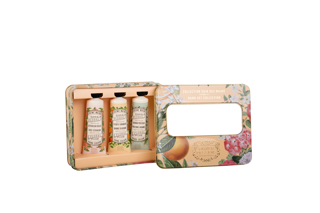 A boxed set of three hand and foot care bottles displayed in an open floral tin box on a white background. The set includes Dr.