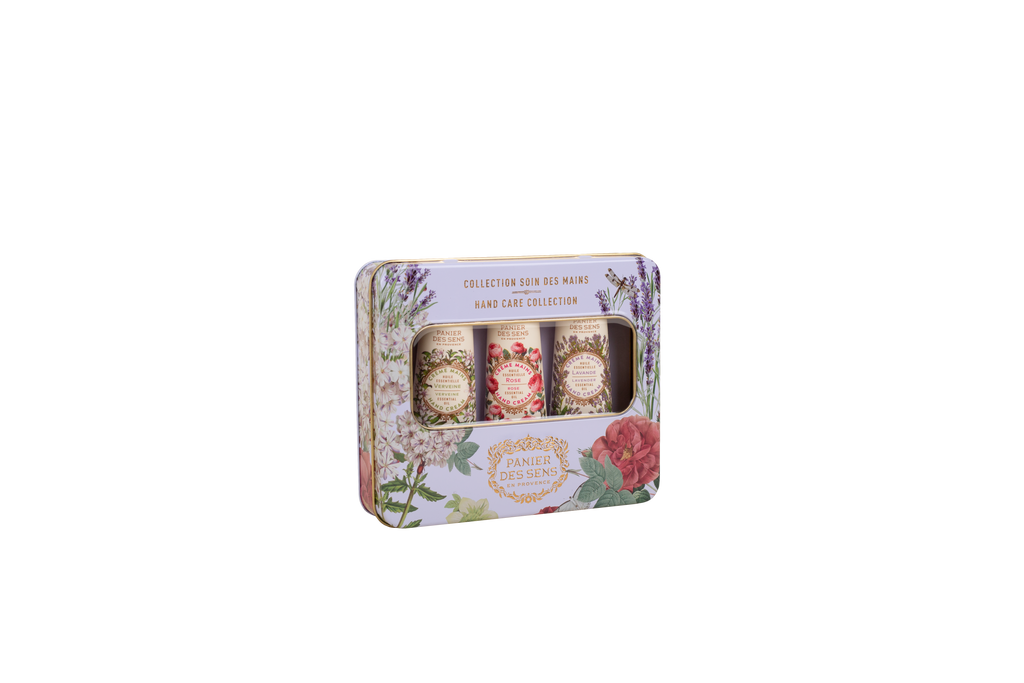 A rectangular decorative tin containing three small cylindrical bottles, shown on a plain white background. The tin has a floral print with lavender, roses, and green leaves, and the label reads 'Collection Soin des Manes Hair Magic' and 'Panachie Collection'.