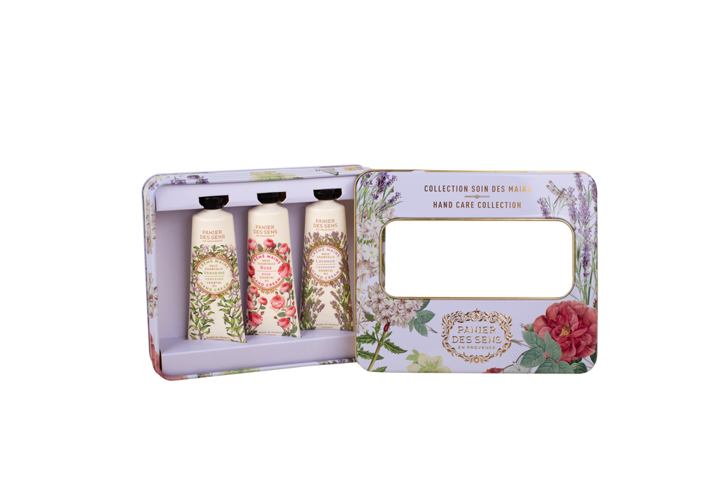 A hand care collection gift set in a floral-patterned metal tin, shown open with three squeeze tubes inside and a mirror on the outer panel.