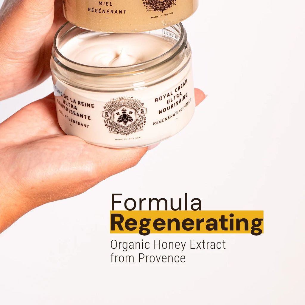 A hand holds an open jar of beeswax candle labeled 'Royal Cream Ultra Nourrissant' and 'Miel Regenerant' against a white background, with text below reading 'Formula Regenerating' and 'Organic Honey Extract from Provence'.