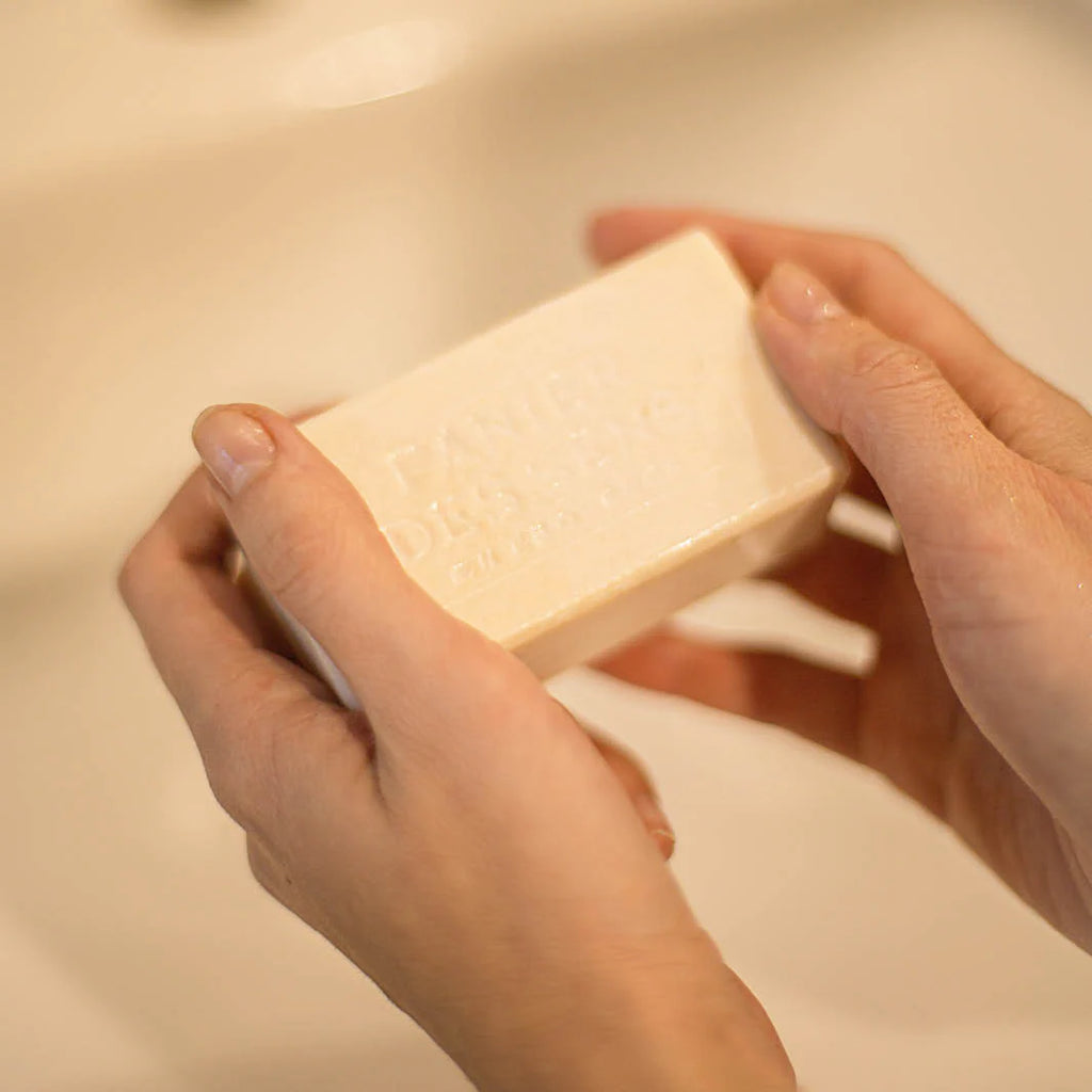 Person holding a bar of soap over a sink