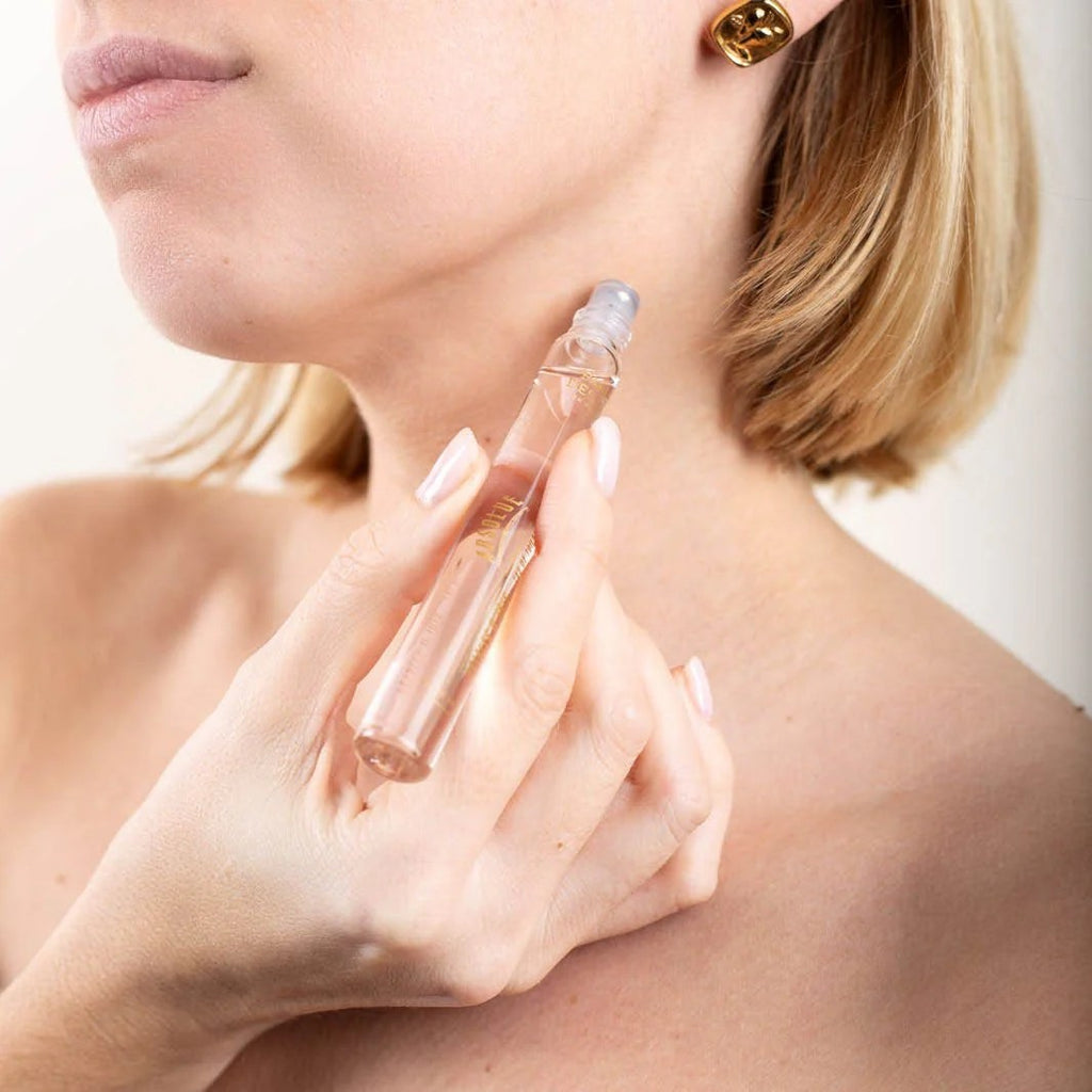 Woman applying perfume to her neck with a clear spray bottle.