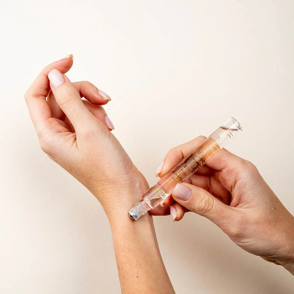 Person applying a clear gel or cream to their wrist using a small applicator.