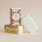 Two bars of soap with floral packaging on a light pink background