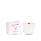 White candle with 'AB' branding next to its packaging on a white background