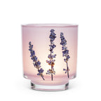 A pink glass candle holder with dried lavender sprigs inside, set against a plain white background.