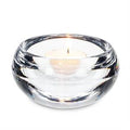 Clear glass candle holder with a lit candle on a white background