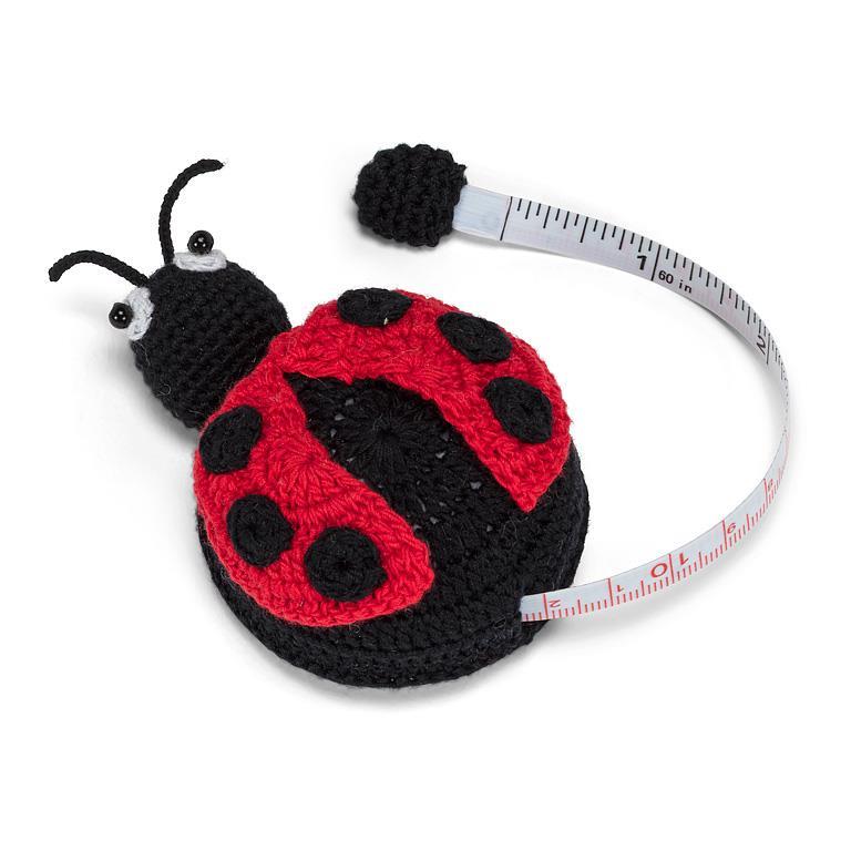 Crocheted ladybug with a measuring tape wrapped around it on a white background