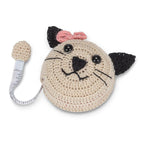 Crocheted cat-shaped toy with a pink bow and measuring tape on a white background