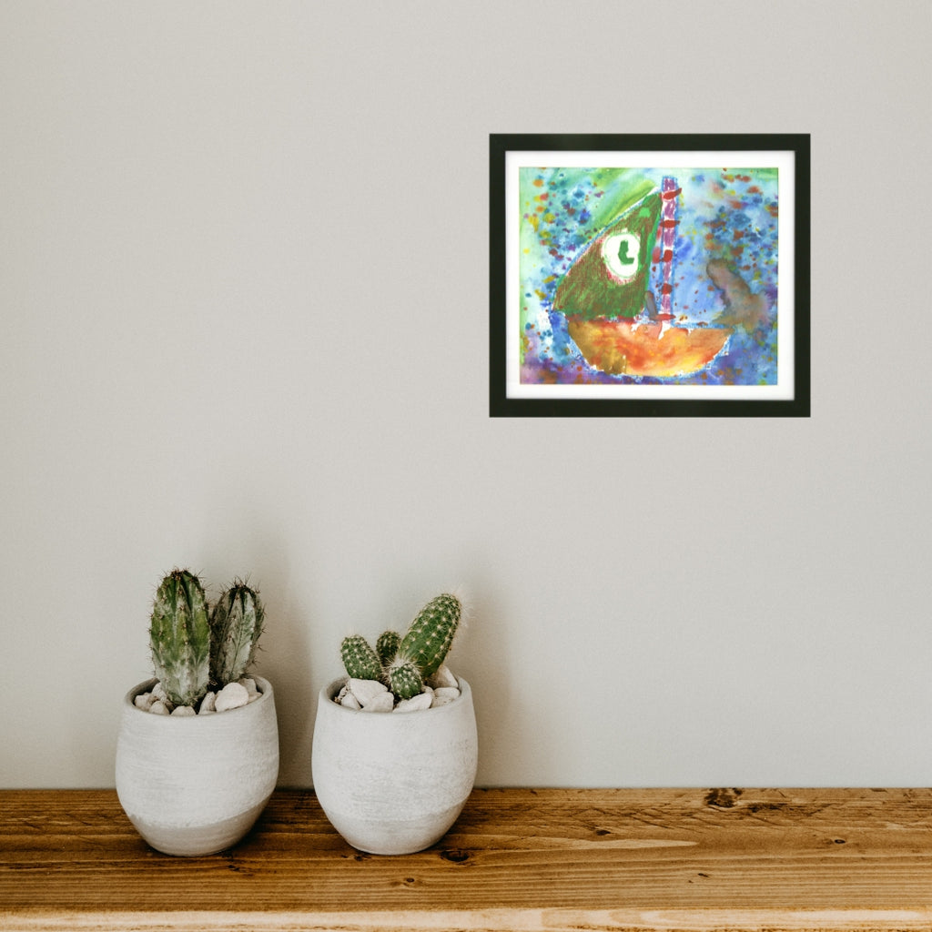 Framed artwork of a colorful boat on a white wall above two potted cacti.