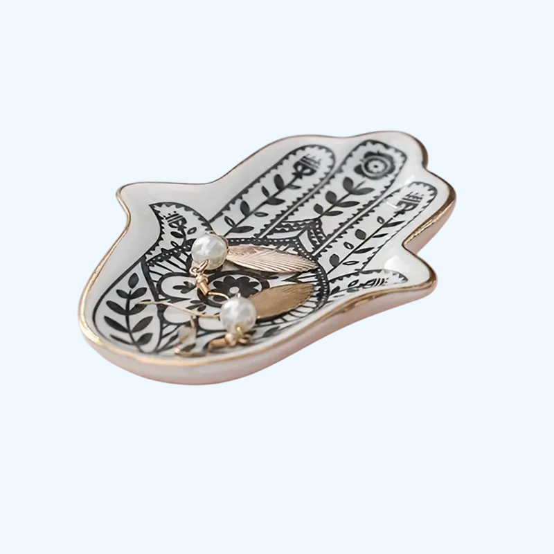 Decorative Hamsa-shaped trinket dish with jewelry on a white background