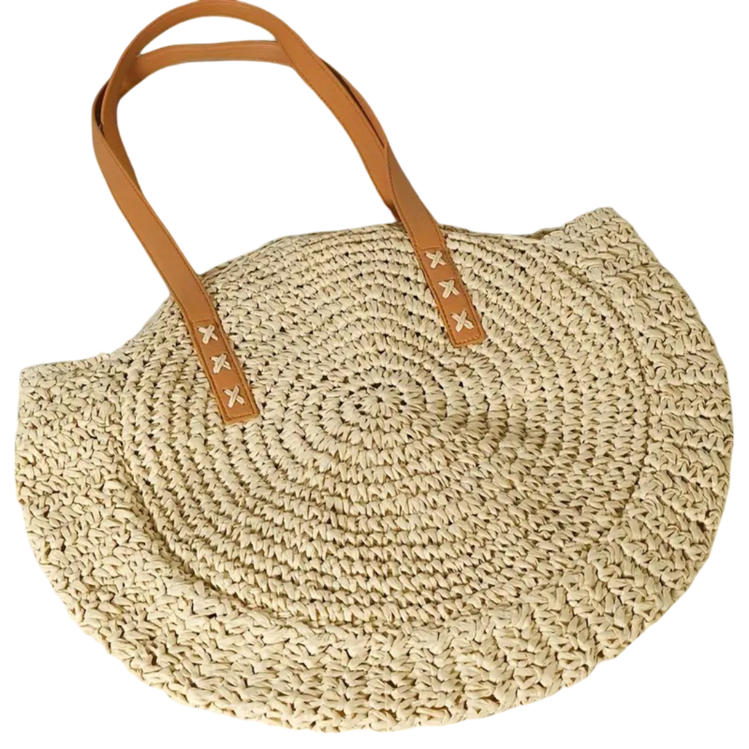 Woven straw bag with brown leather handles on a white background
