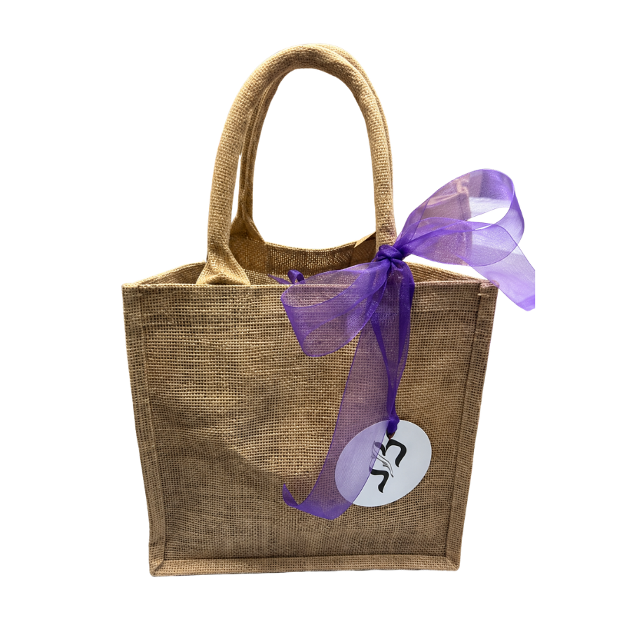 Brown jute bag with a purple ribbon and a white tag on a white background