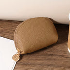 Brown leather pouch with gold zipper on a wooden surface