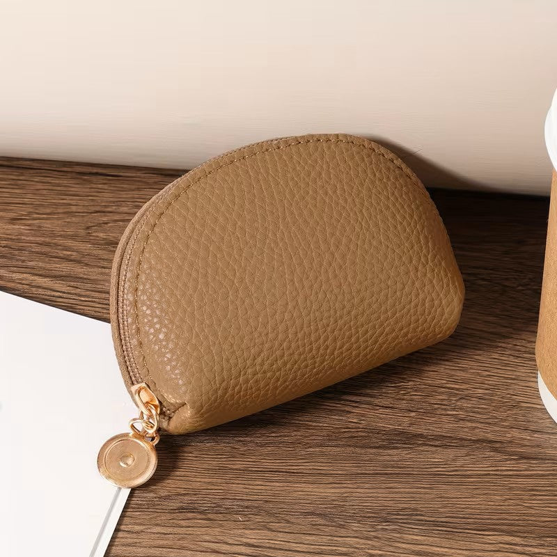 Brown leather pouch with gold zipper on a wooden surface