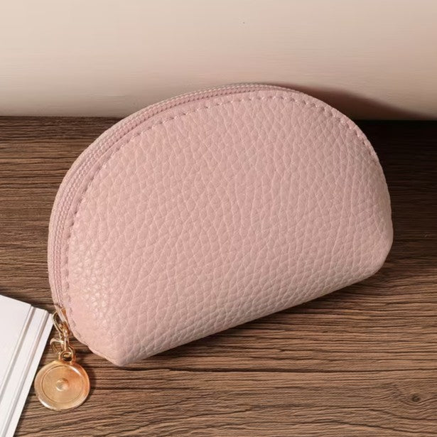 Pink textured pouch with a gold zipper on a wooden surface