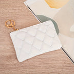 White marble-textured pouch with gold keychain on a wooden surface