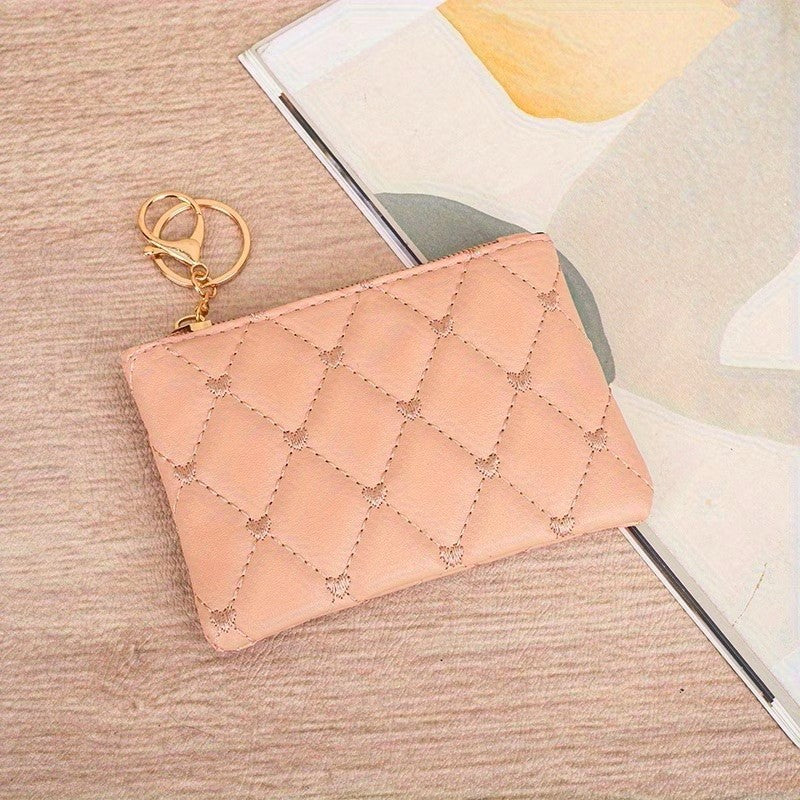 Quilted pink pouch with gold keychain on a textured surface