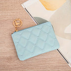 Light blue quilted pouch with gold keychain on a wooden surface