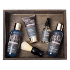 Men's grooming products including bath wash, lotion, oil, and brush in a wooden tray.