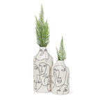 Two white vases with black line art faces and green plants on a white background