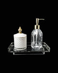 Bathroom accessories set with a clear soap dispenser and white container on a black background
