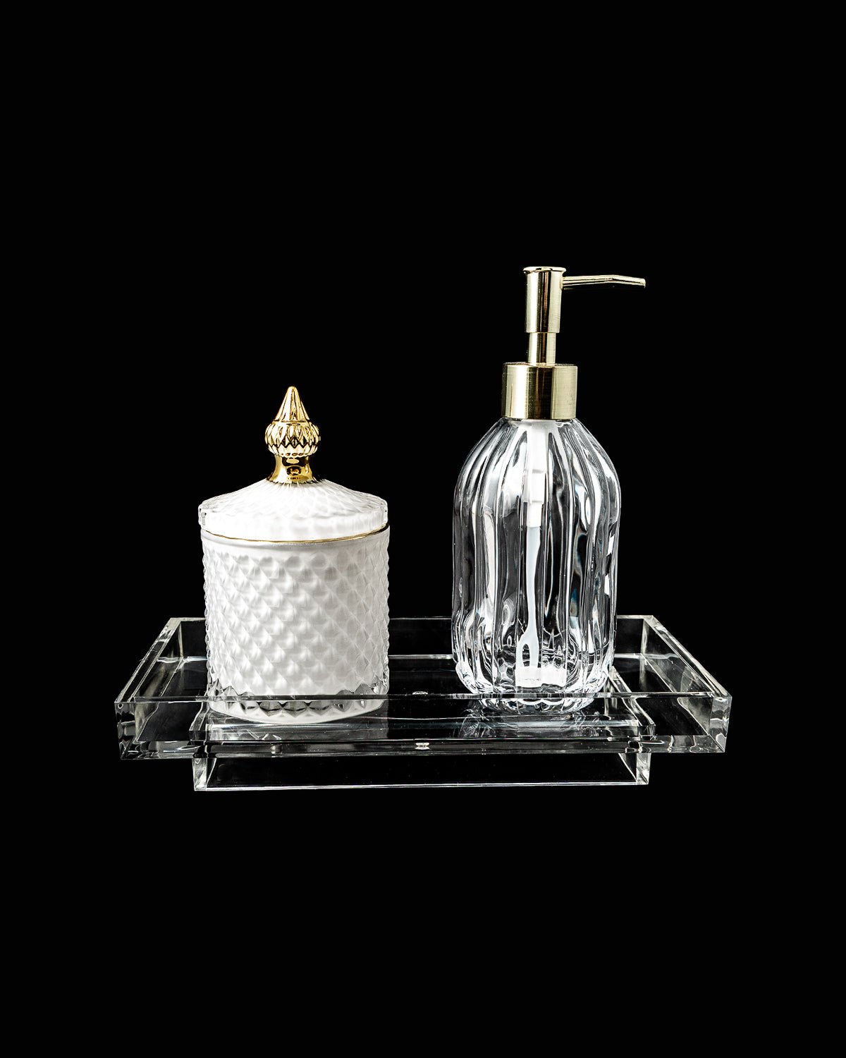 Bathroom accessories set with a clear soap dispenser and white container on a black background