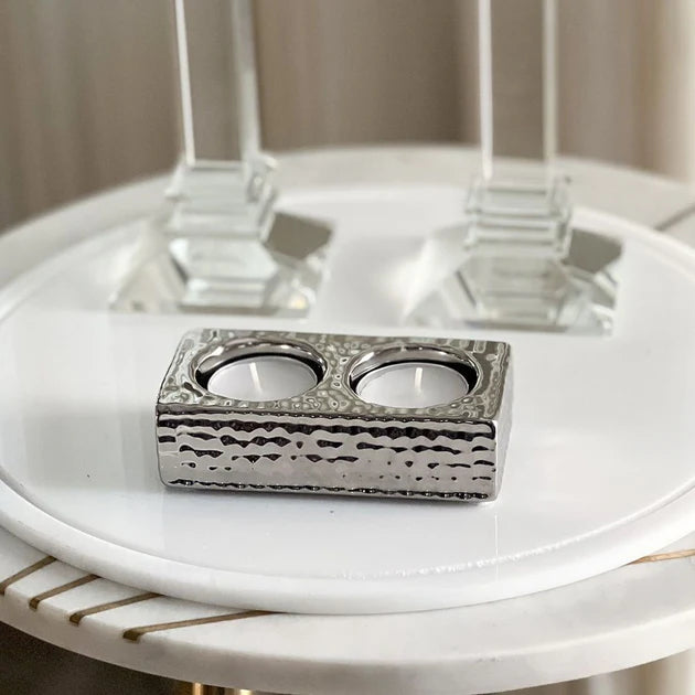Silver candle holder on a white surface with a blurred background