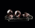 Three purple glass vases on a clear acrylic stand against a black background