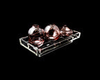 Three round glass vases on a clear rectangular tray against a black background