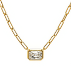 A gold paperclip chain necklace with a rectangular bezel-set clear gemstone pendant, shown against a plain white background.