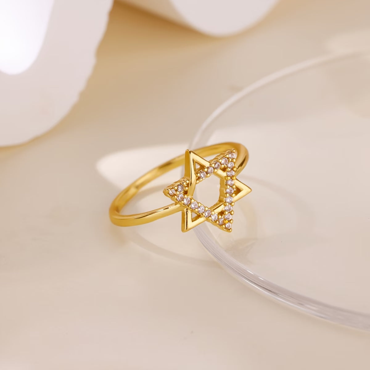 Gold ring with a geometric design on a light beige background