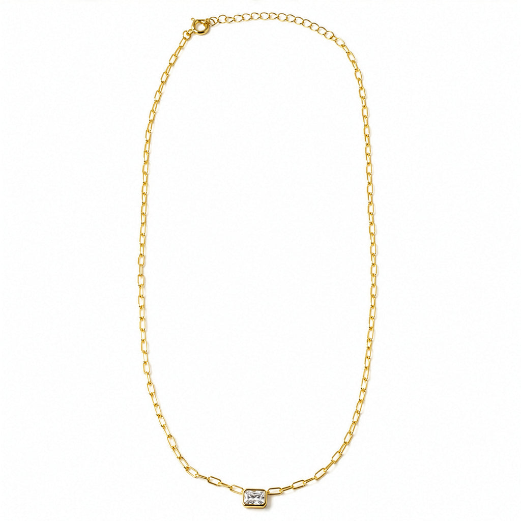 A delicate gold chain necklace with a small rectangular bezel-set clear gemstone pendant, displayed on a clean white background.