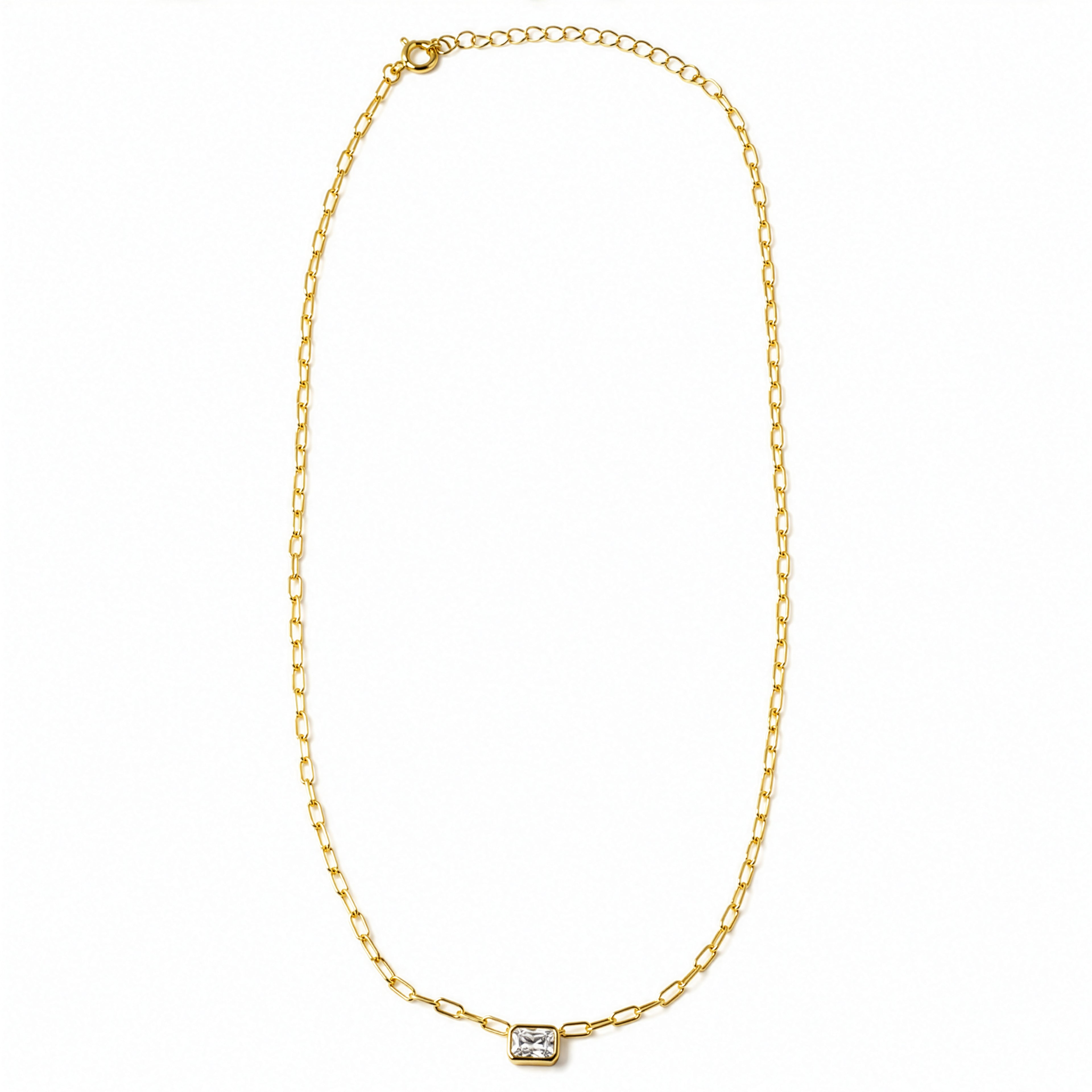A delicate gold chain necklace with a small rectangular bezel-set clear gemstone pendant, displayed on a clean white background.