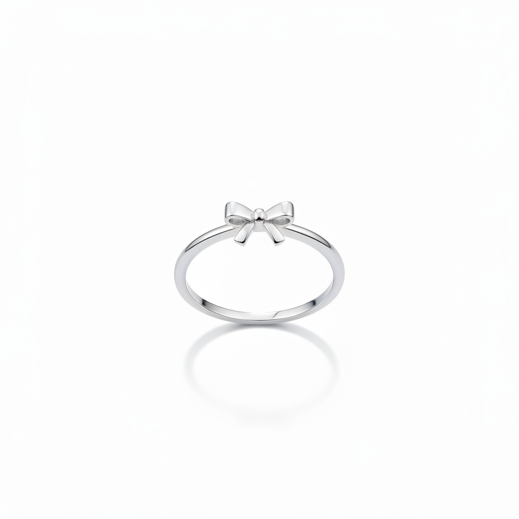 Silver ring with a bow design on a person's finger against a white background