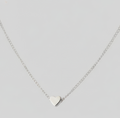 A delicate silver chain necklace with a small, polished silver heart pendant, displayed against a solid light gray background.