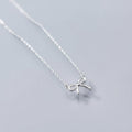 Silver bow necklace on a light gray background