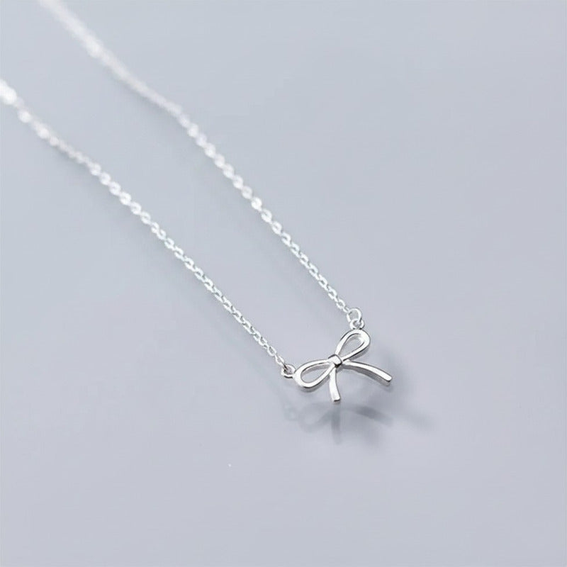 Silver bow necklace on a light gray background
