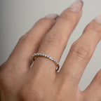 Close-up of a hand wearing a diamond ring on a neutral background