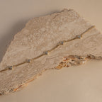 Gold necklace with small diamonds on a textured beige surface