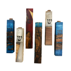 Six decorative wooden mezuzah cases with different wood grain patterns and blue Hebrew lettering, displayed against a plain white background.