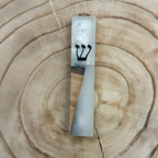 A rectangular mezuzah case made of white and gray marbled resin with a light wood inlay and a black Hebrew letter 'Shin', displayed on a natural wood slice background.
