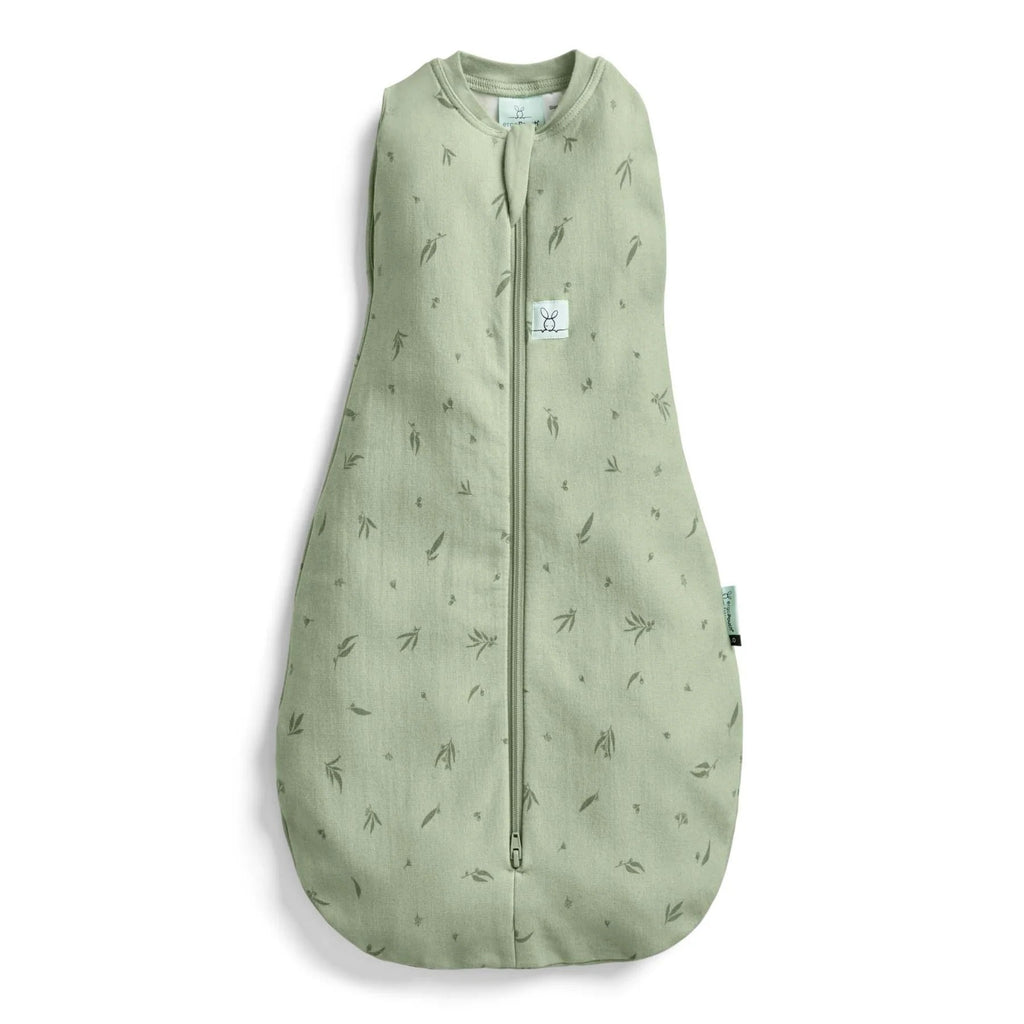A sage green baby sleep sack with a subtle all-over leaf print, featuring a front zipper closure and a small white brand label on the chest.