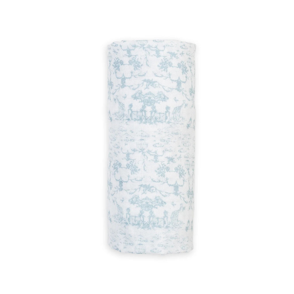 A rolled-up white muslin swaddle blanket or baby wrap, featuring a light blue toile de Jouy pattern of figures and trees, shown against a plain white background.