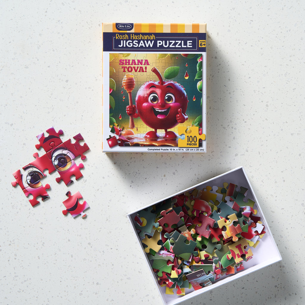 A boxed jigsaw puzzle called 'Shana Tova', shown on a light speckled surface with several loose puzzle pieces beside the box and an open box filled with multicolored puzzle pieces.