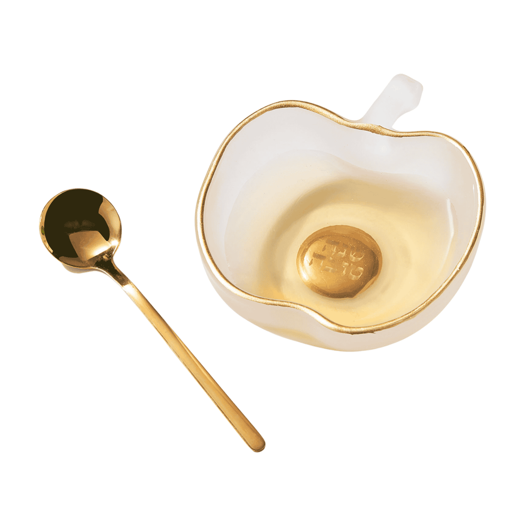 A white apple-shaped bowl with a gold rim and a gold spoon, shown on a clean white background.