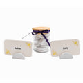 A set of personalized wooden name cards for guests, shown with two cream-colored cards labeled 'Bubby' and 'Zaidy' with gold bee illustrations, and a clear glass jar filled with round white wooden tokens tied with a dark purple ribbon and topped with a light wood lid.