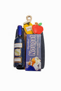 A bottle of wine on a marble and wood cutting board, with a box of nougat and two cookies. 