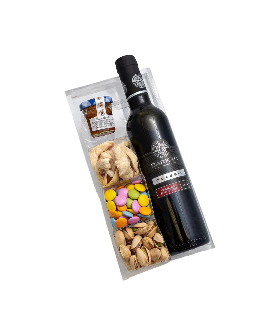 A gourmet gift hamper featuring a bottle of Barami Classic Red Wine, a small jar of honey, pistachios, dried apricots, and colorful candy-coated chocolates in a clear plastic box, set against a plain white background.
