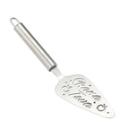 A stainless steel cake server with a cylindrical handle and a flat, wide serving blade. The blade features custom laser-cut cursive text reading 'Shana Tova' with decorative dots and a small apple motif, set against a clean white background.